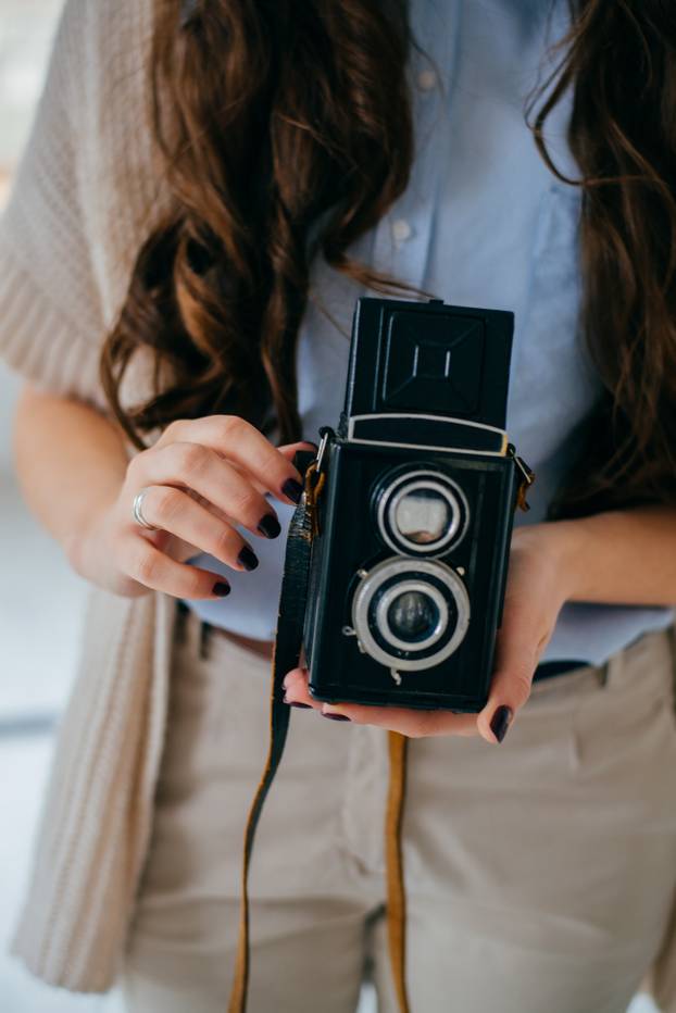 on a white background young girl with long hair with an old camera