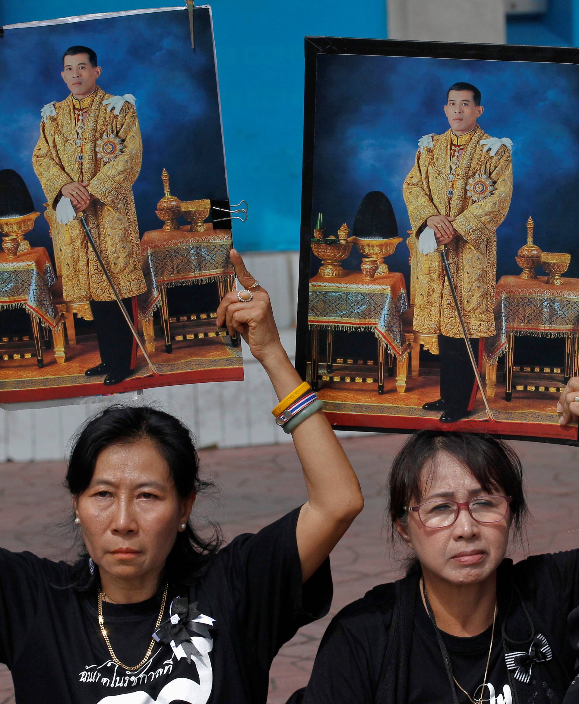 Well-wishers hold up pictures of Thailand's new King Maha Vajiralongkorn Bodindradebayavarangkun before he leaves the Grand Palace in Bangkok, Thailand