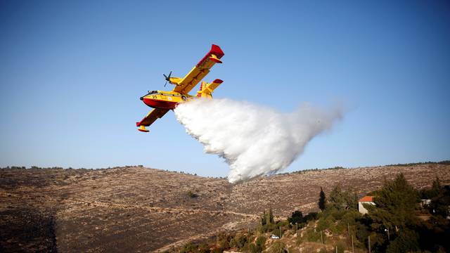 A foreign firefighting plane drops fire retardant during a wildfire, around the communal settlement of Nataf, close to Jerusalem