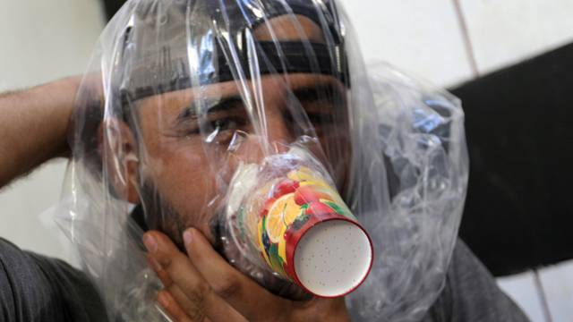 Hudhayfa al-Shahad tries an improvised gas mask in Idlib