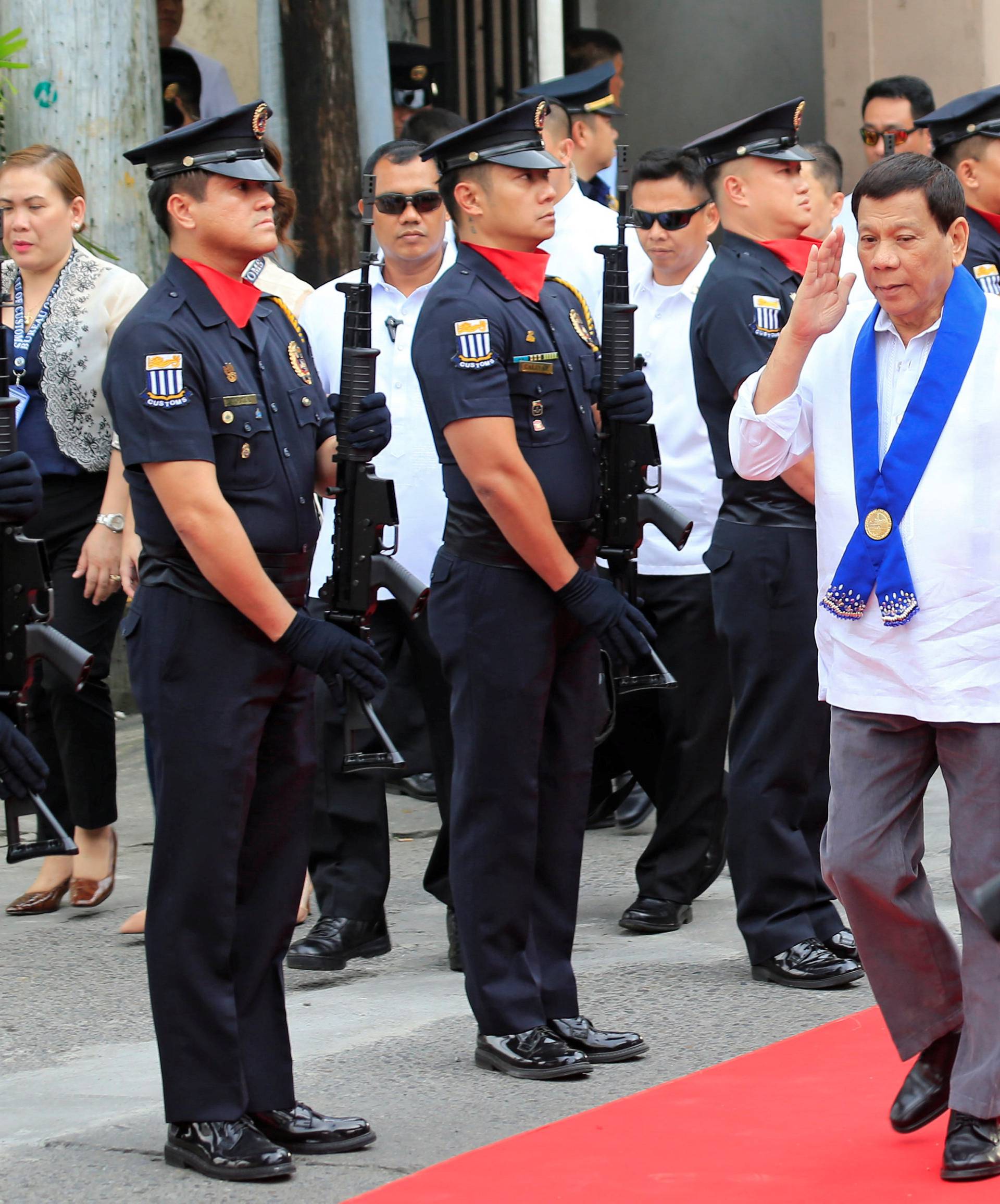 President Rodrigo Duterte salutes while passing members of custom police, upon arrival to witness the destruction of condemned smuggled luxury cars worth 61,626,000.00 pesos (approximately US$1.2 million), in Metro Manila