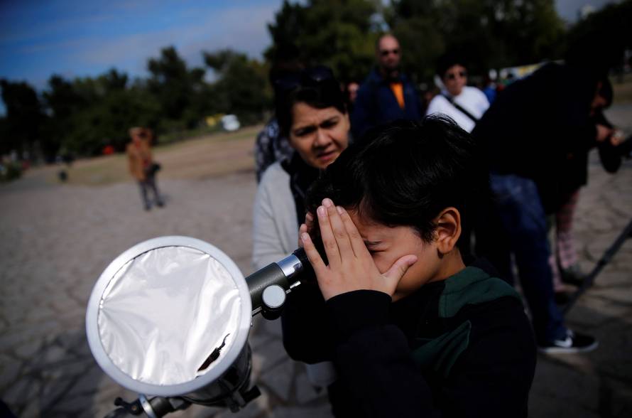 A boy uses a telescope to observe the planet Mercury transit in front of the sun outside Buenos Aires' planetarium