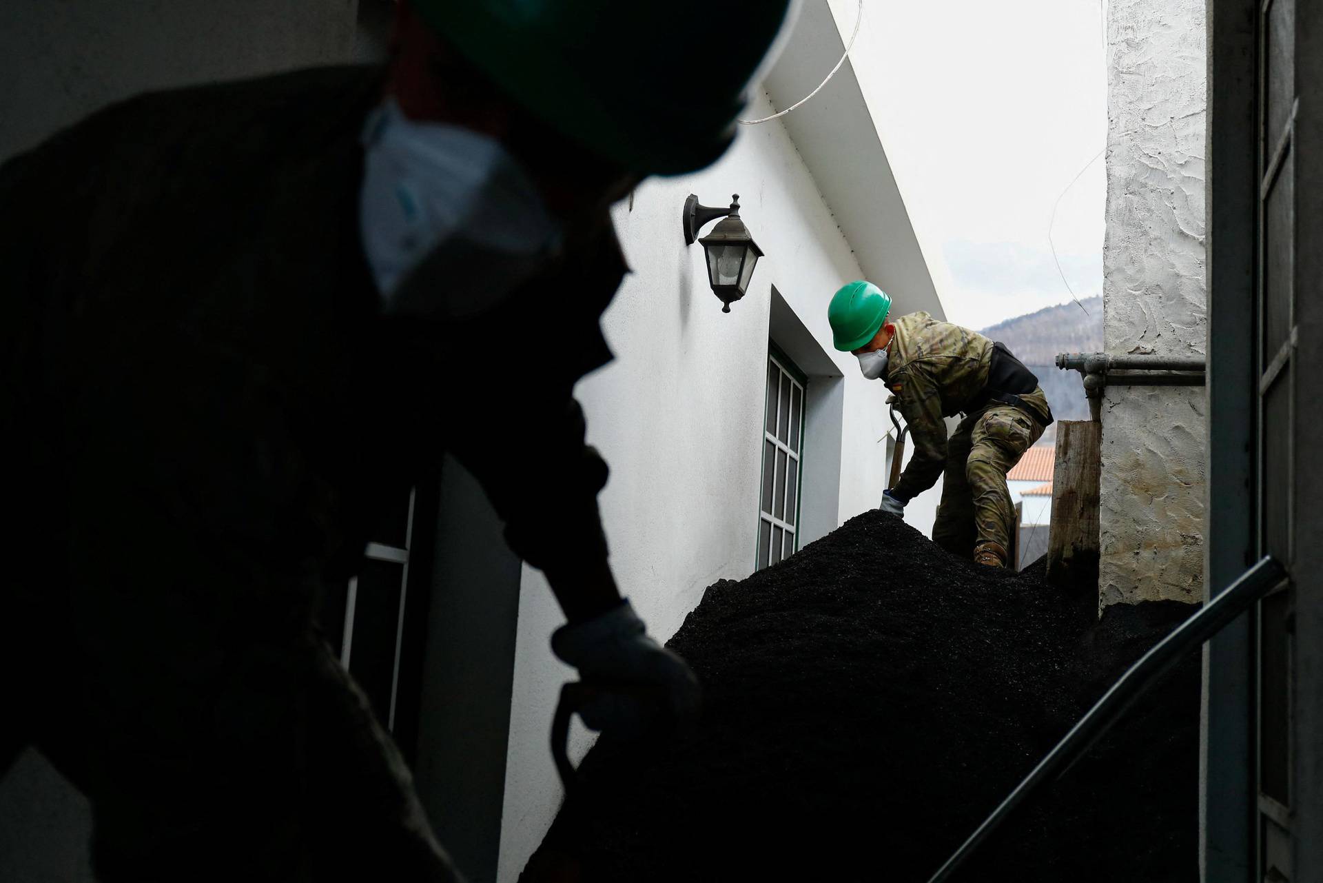 Spanish military clean the ash from the Cumbre Vieja volcano that surrounds a house in Las Manchas