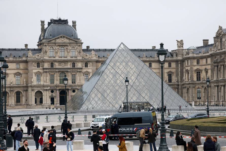 Police stand near the pyramid of the Louvre museum after reports of a robbery, in Paris
