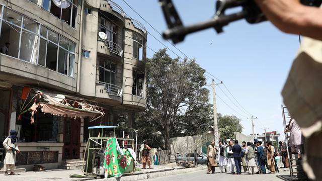 Taliban fighters stand guard at the site of explosions at Sikh Temple in Kabul