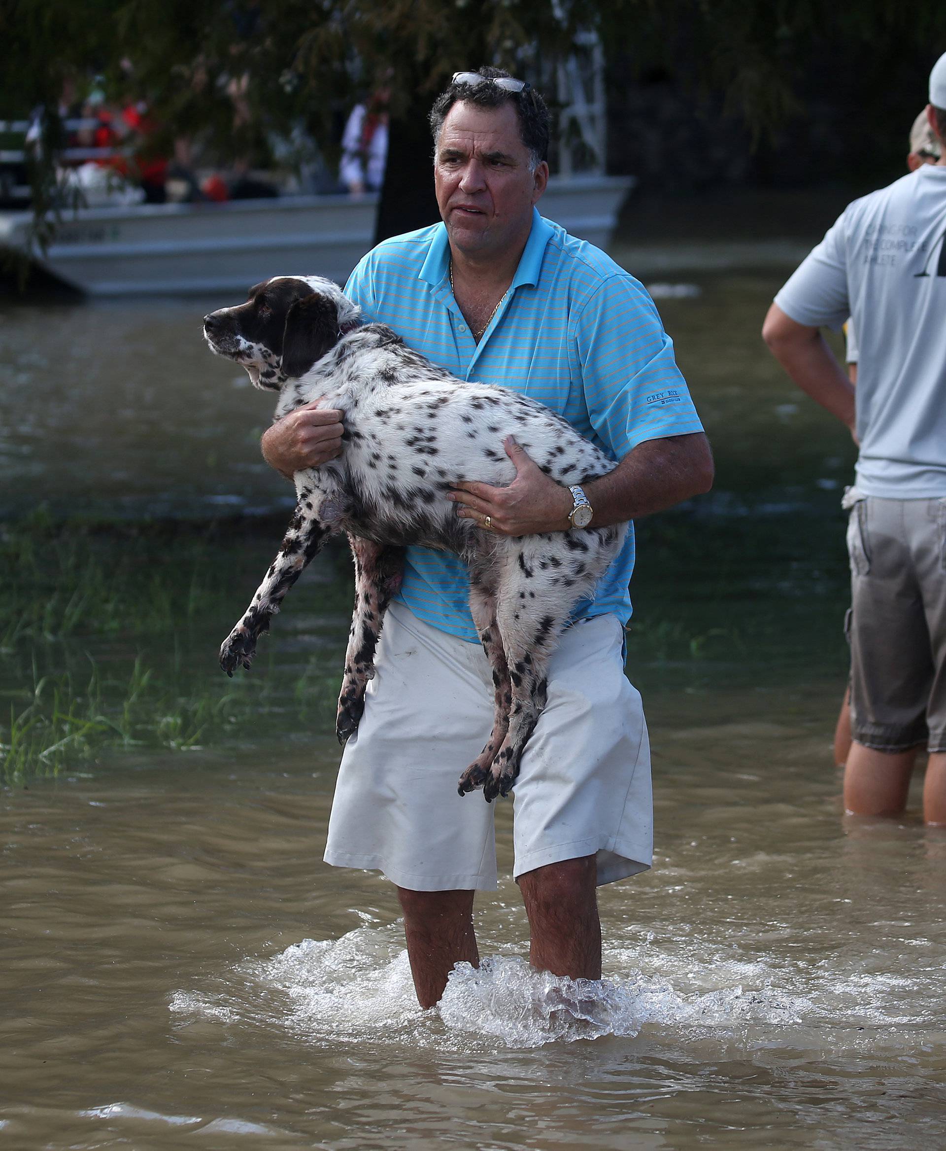 A man carries his dog through flood water after being evacuated from the rising water following Hurricane Harvey in a neighborhood west of Houston, Texas