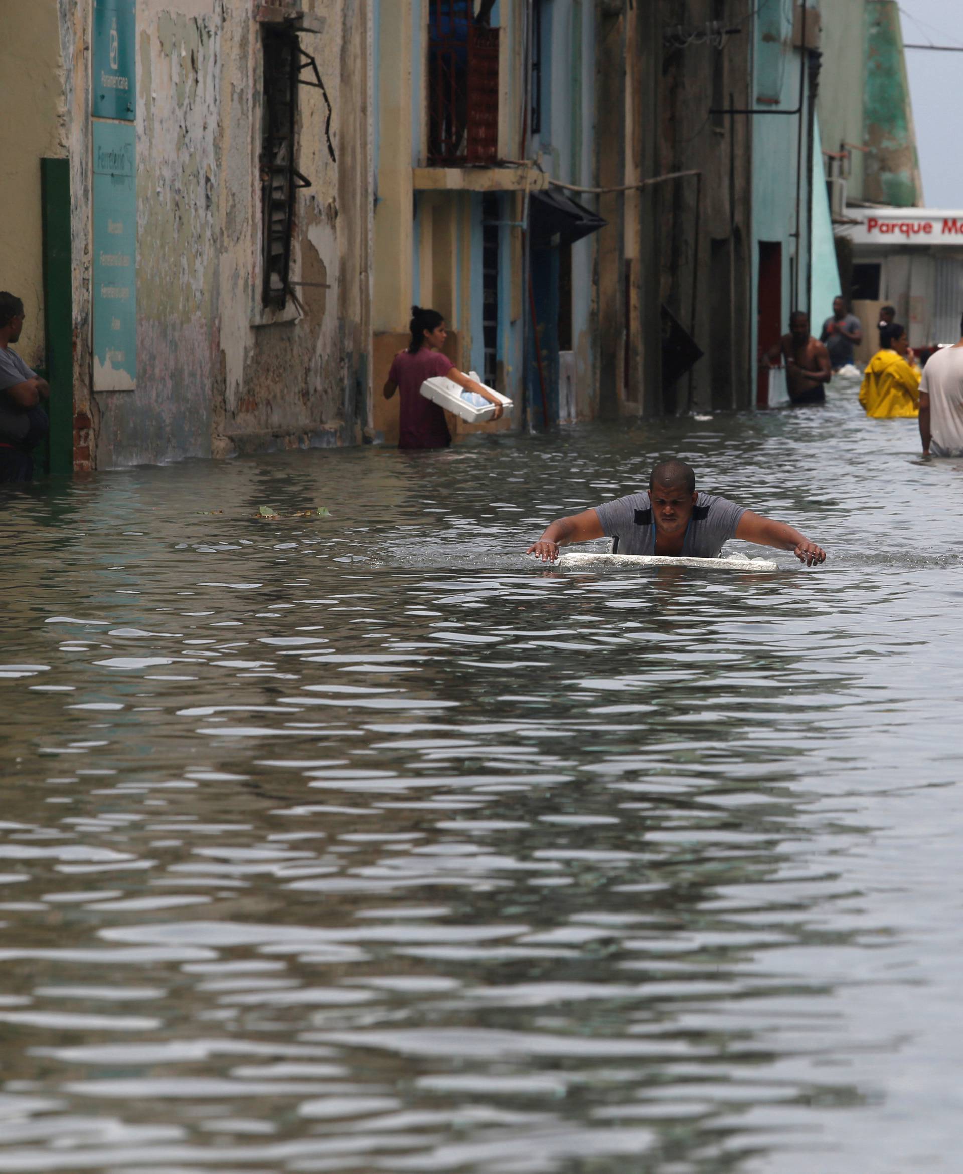 A man uses a piece of foam board to get through a flooded street, after the passing of Hurricane Irma, in Havana