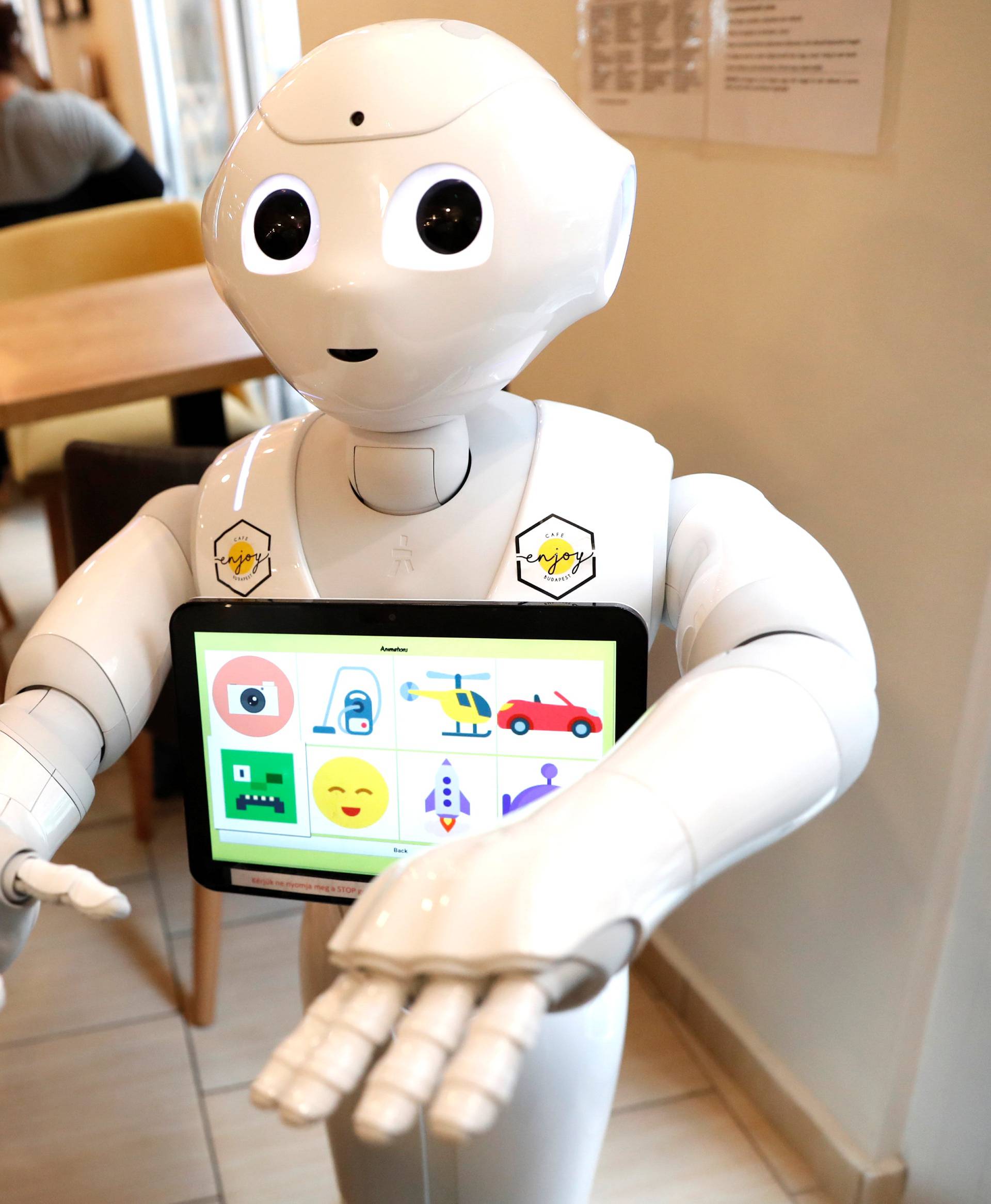 Children stand next to Pepper the robot at a cafe in Budapest