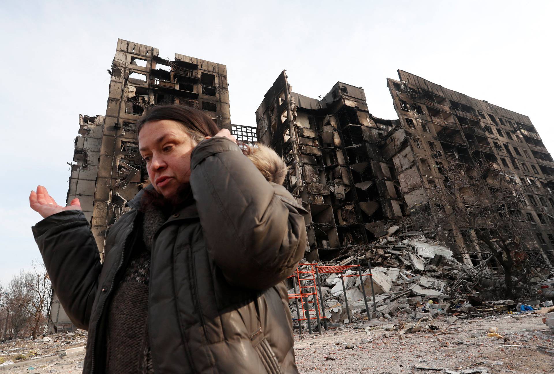 Nurse Svetlana Savchenko stands next to the destroyed building where her apartment was located in Mariupol