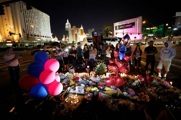 People gather at a makeshift memorial in the middle of Las Vegas Boulevard following the mass shooting in Las Vegas