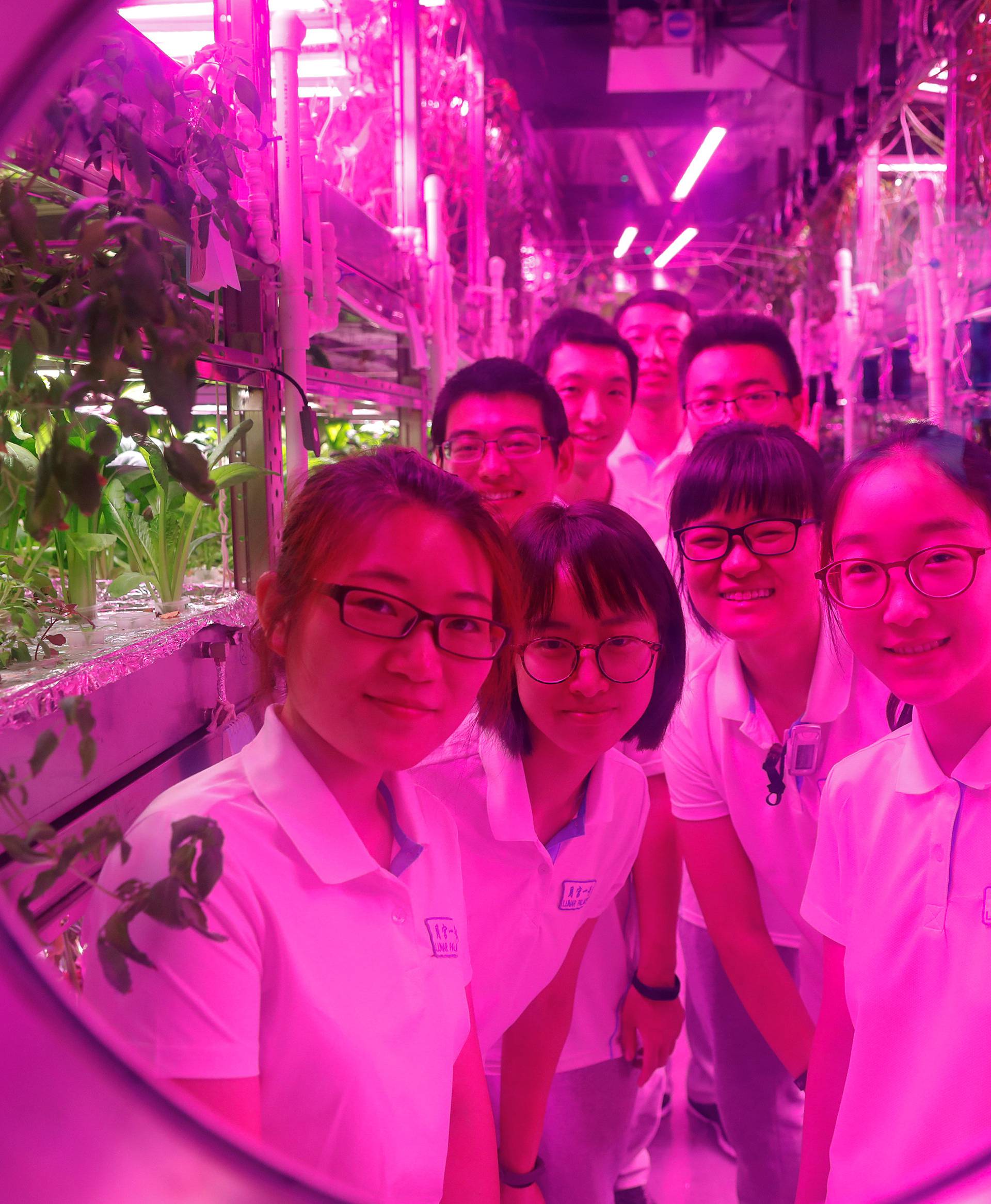 Volunteers smile from inside a simulated space cabin in which they temporarily live as a part of the scientistic Lunar Palace 365 Project, at Beihang University in Beijing