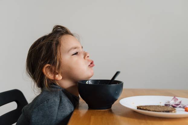 Unhappy,Child,Girl,Eats,Soup,From,Black,Bowl,With,Bread