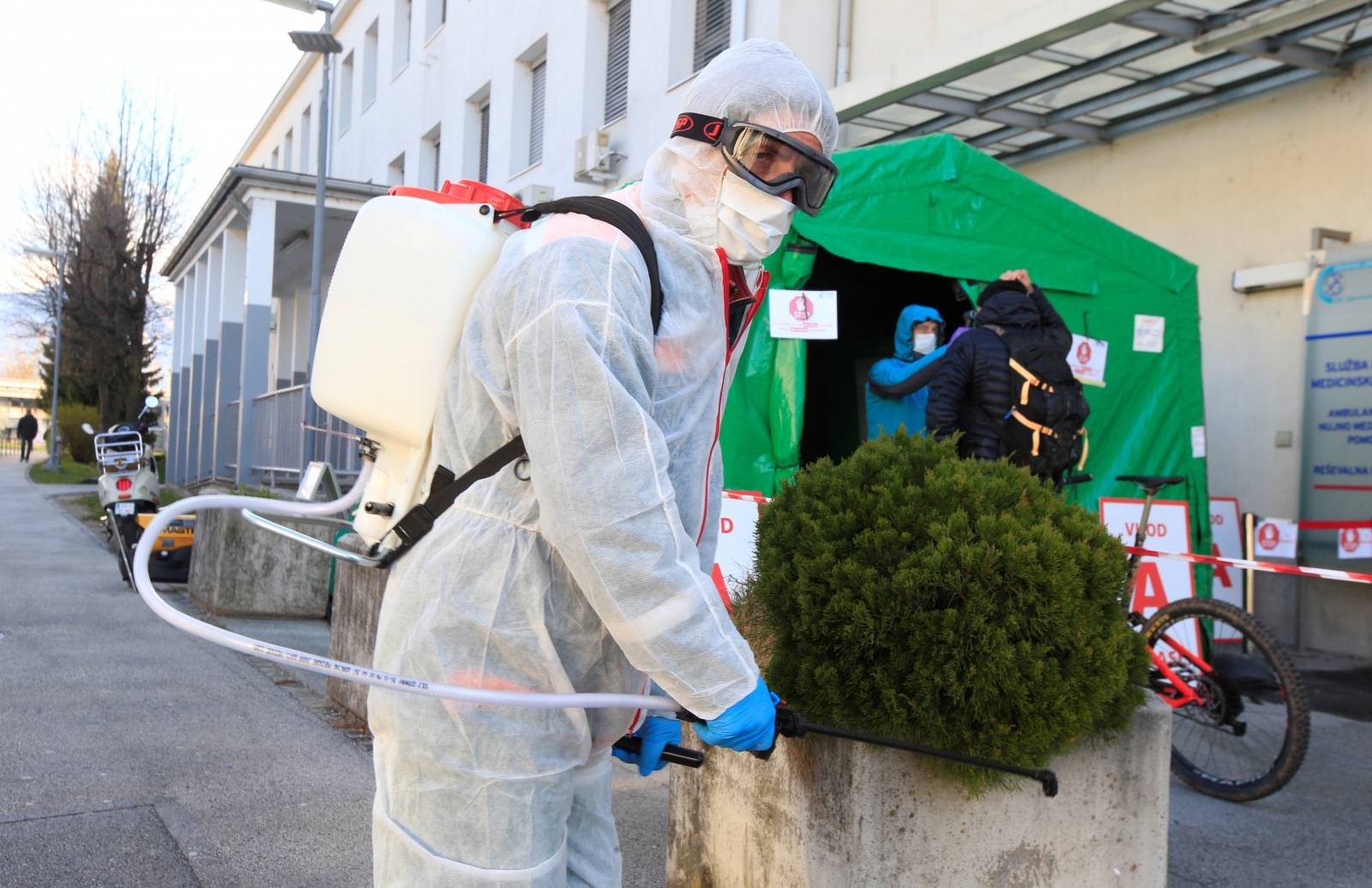 A worker sprays disinfectant to prevent the spread of coronavirus disease (COVID-19), outside the hospital in Kranj