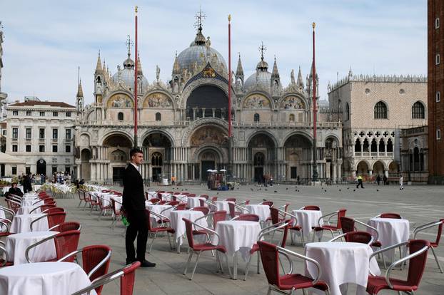 A waiter stands by empty tables outside a restaurant at St Mark