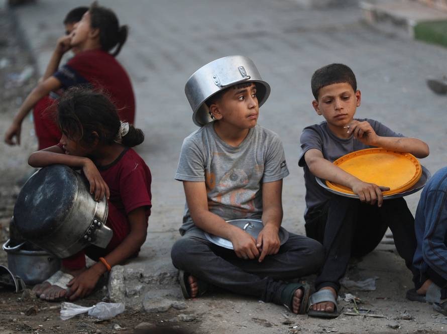 Palestinians wait to receive food from a charity kitchen, amid a hunger crisis, in Gaza City
