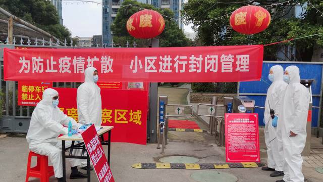 FILE PHOTO: Workers in protective suits are seen at a checkpoint for registration and body temperature measurement, at an entrance to a residential compound in Wuhan