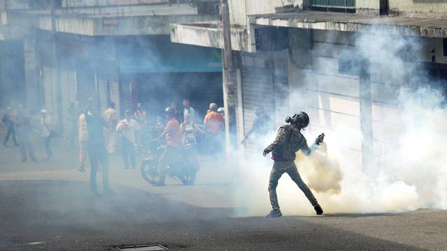 A demonstrator throws back a gas canister while clashing with security forces during a rally in Tachira