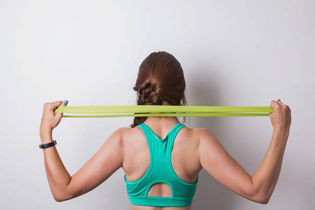 Woman stretching rubber band behind her back.