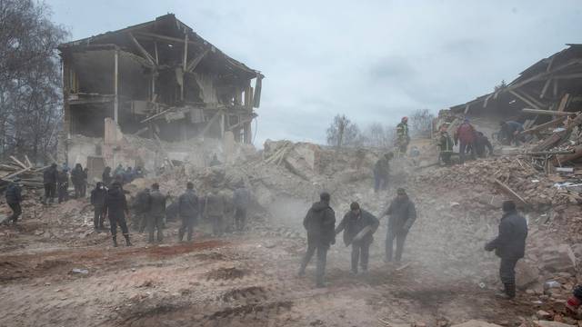 People remove debris at the site of a military base building that, according to the Ukrainian ground forces, was destroyed by an air strike, in the Sumy region