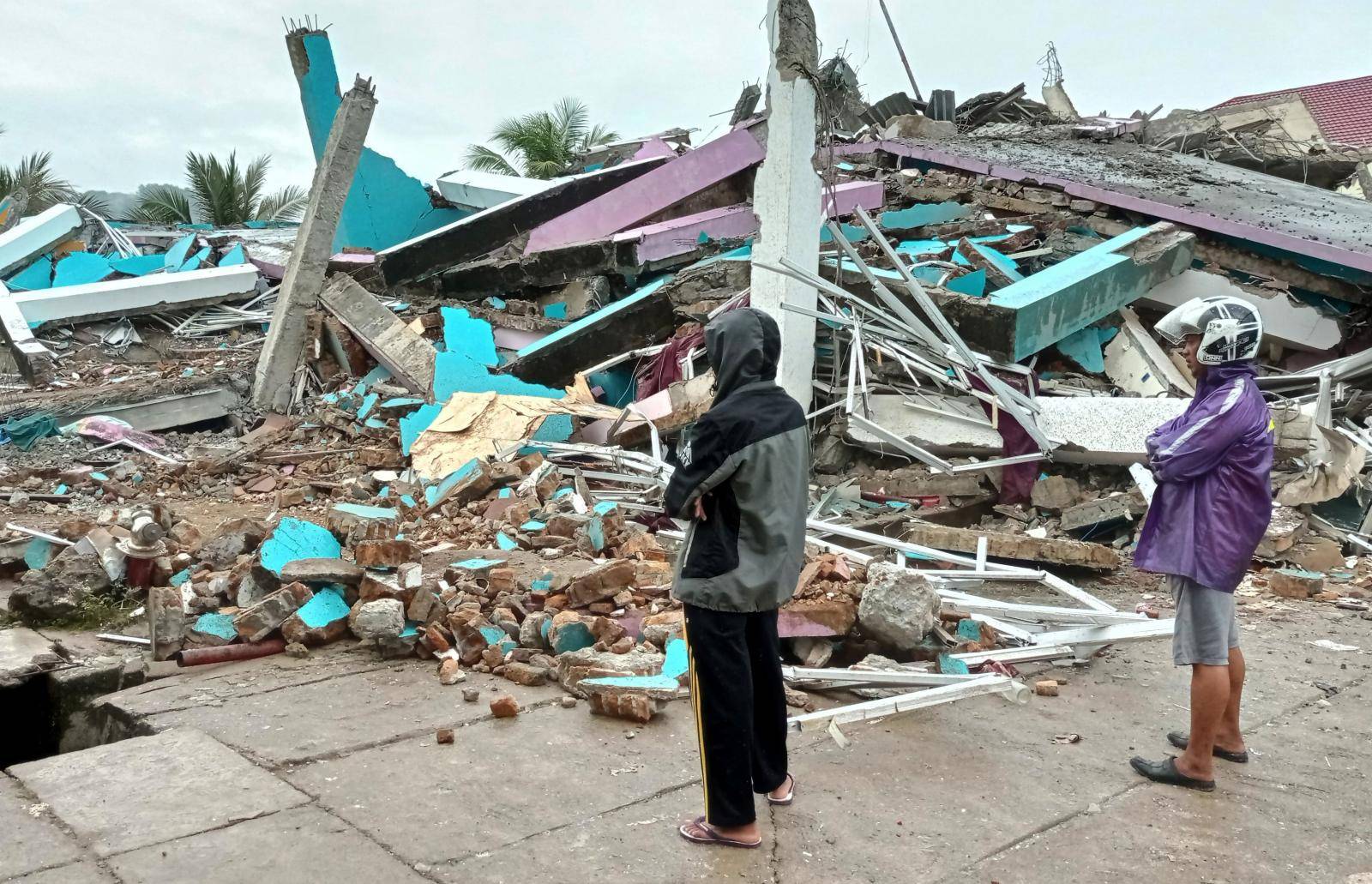 People look at a damaged hospital building following an earthquake in Mamuju