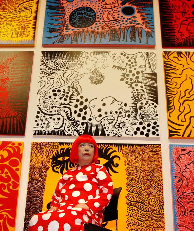 Artist Yayoi Kusama poses for a photograph with her artwork "Love arrives at the Earth Carrying with it a Tale of the Cosmos" at the Tate Modern gallery in London
