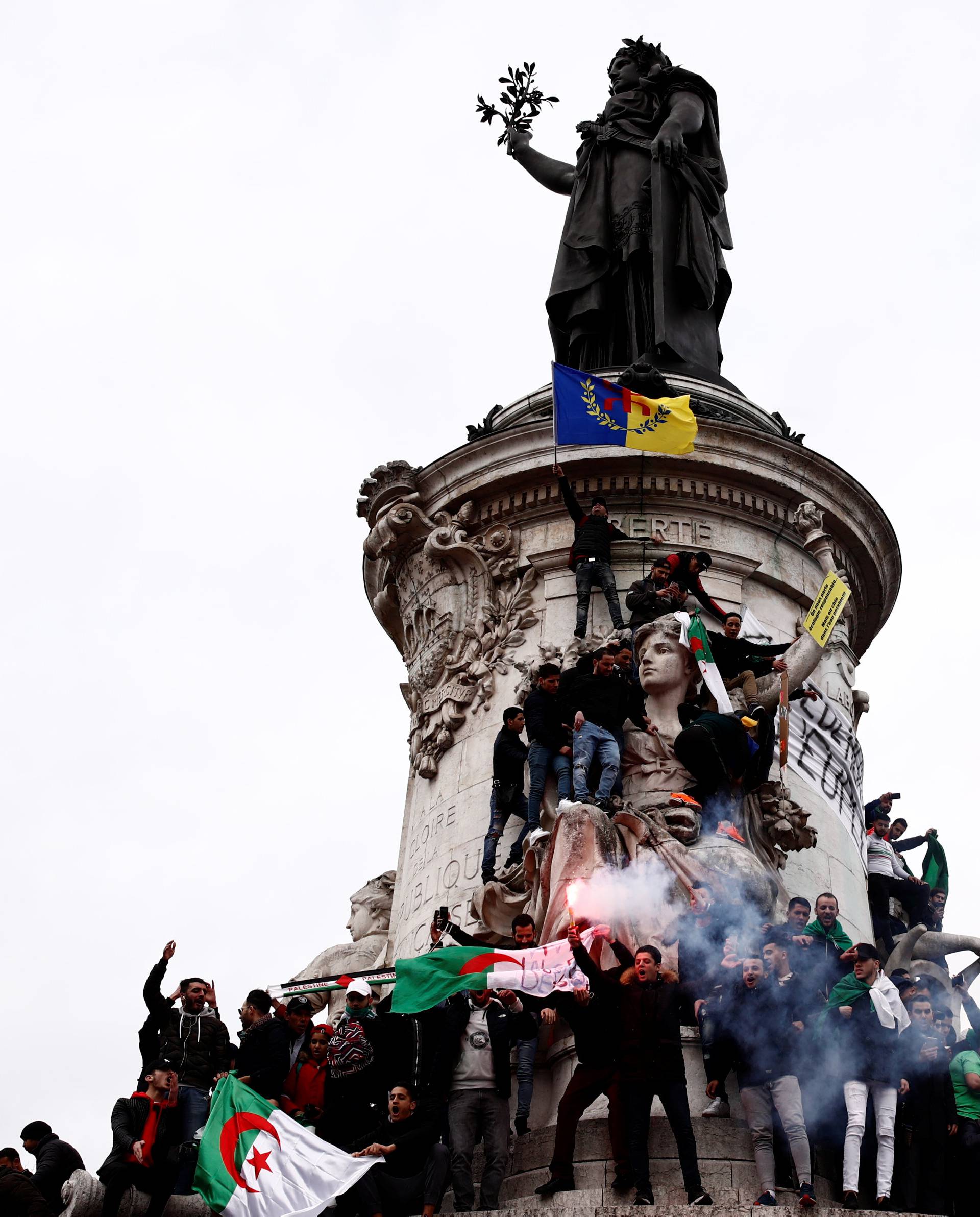 Demonstrators stand on the Monument to the Republic during a protest against Algerian President Abdelaziz Bouteflika seeking a fifth term in a presidential election in Paris