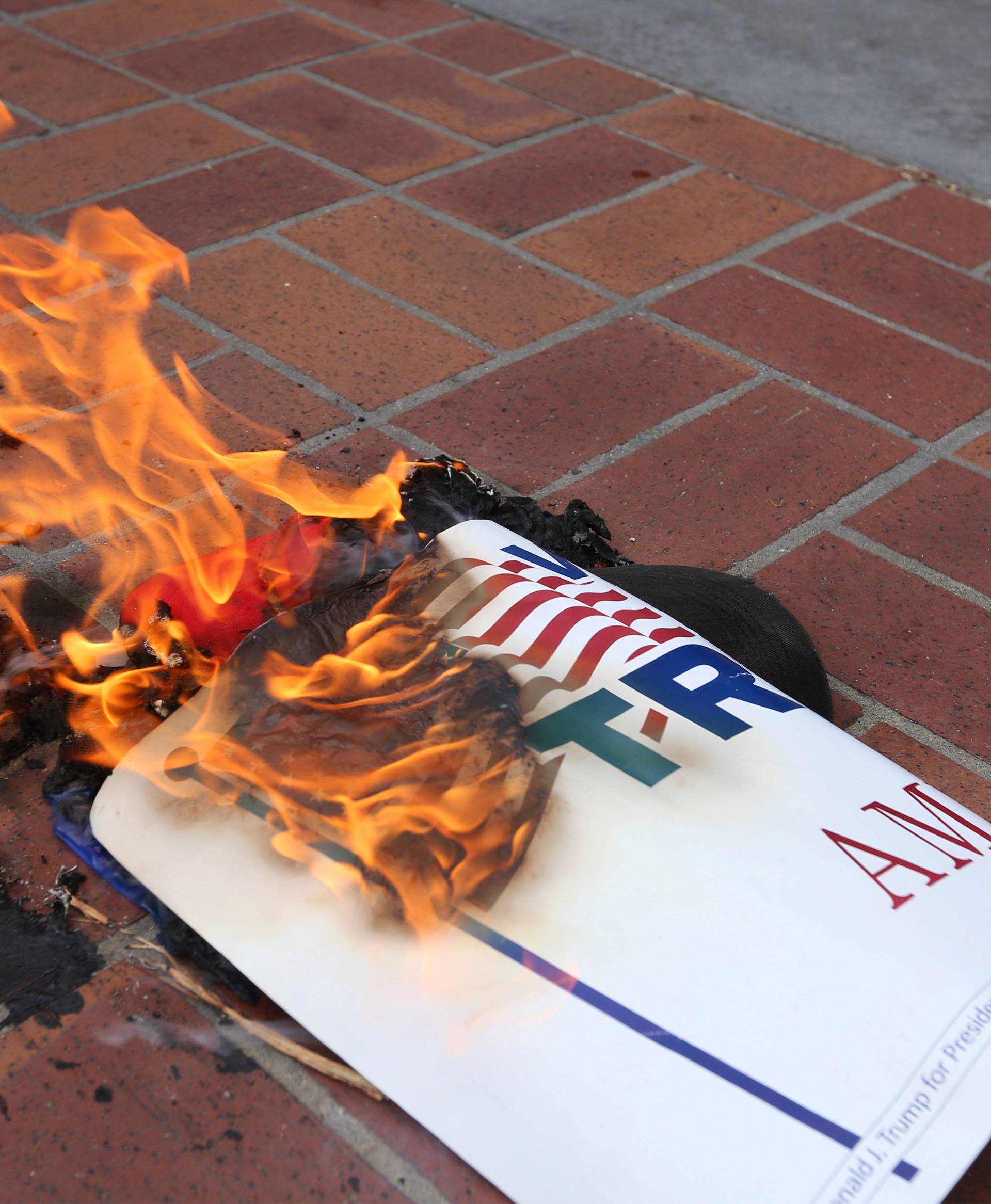 Anti-Trump demonstrators burn Trump's campaign items outside a campaign event for Republican U.S. presidential candidate Donald Trump in San Diego