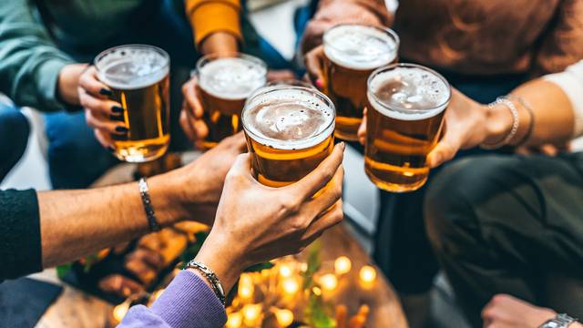 Group,Of,Friends,Drinking,And,Toasting,Glass,Of,Beer,At