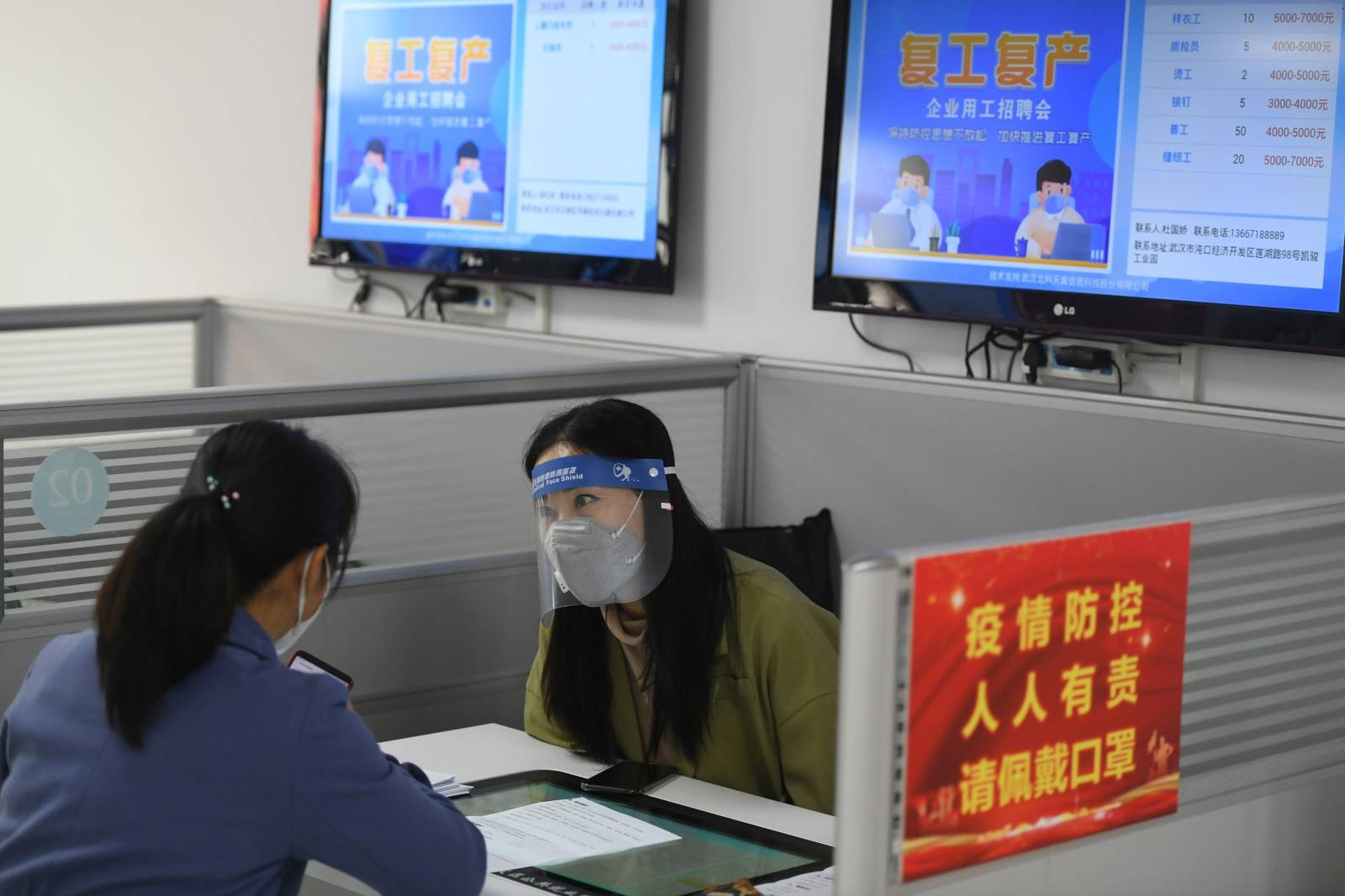 Staff member wearing a protective face mask and a face shield talks to an applicant at a job fair after the lockdown was lifted in Wuhan of Hubei province, China's epicentre of the novel coronavirus disease (COVID-19) outbreak