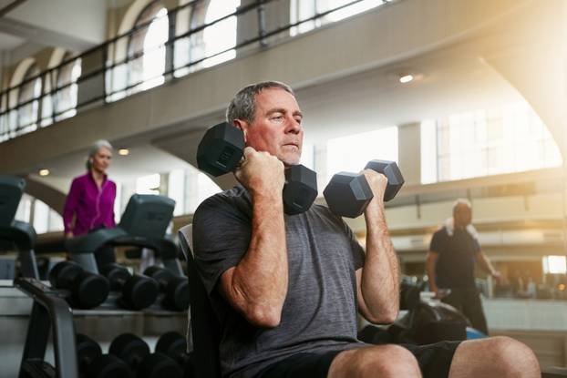 Lifting is not only for the young. a senior man working out with weights at the gym.