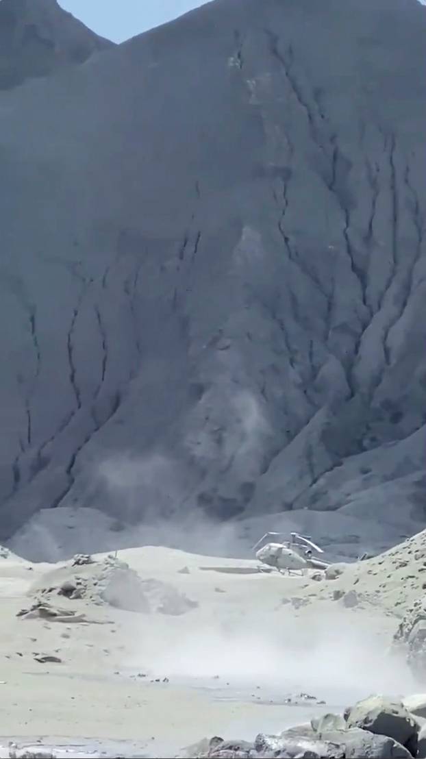 A helicopter damaged by the volcanic eruption of Whakaari, also known as White Island, is seen amid smoke in New Zealand