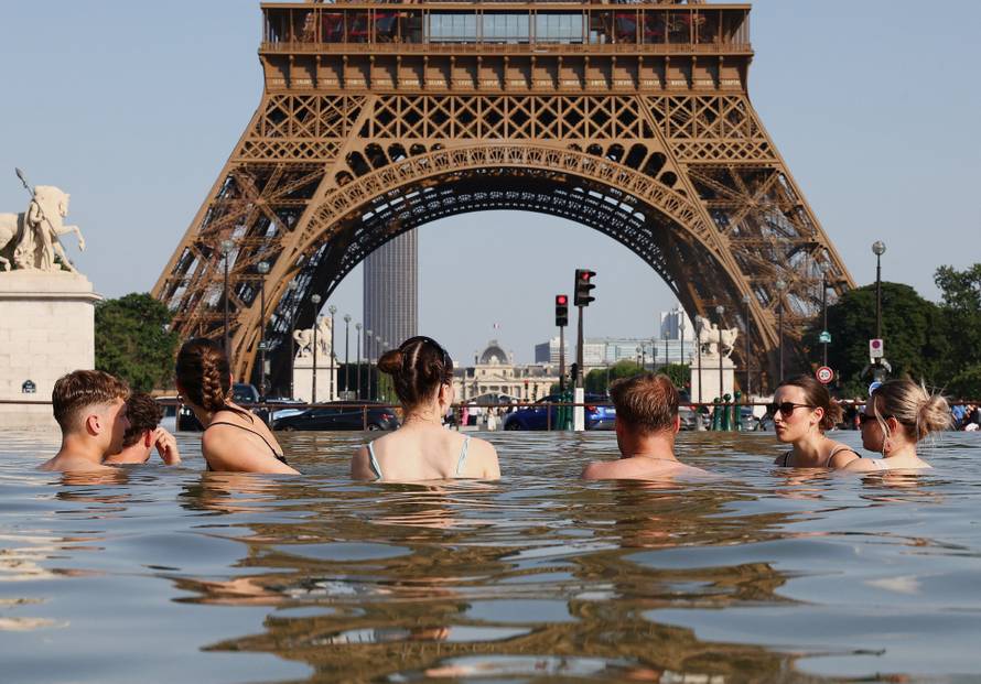 People cool off in the Trocadero Fountain next to the Eiffel Tower in Paris