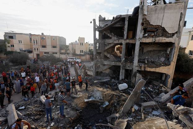 Palestinians search for casualties under the rubble of a building destroyed by Israeli strikes in Khan Younis