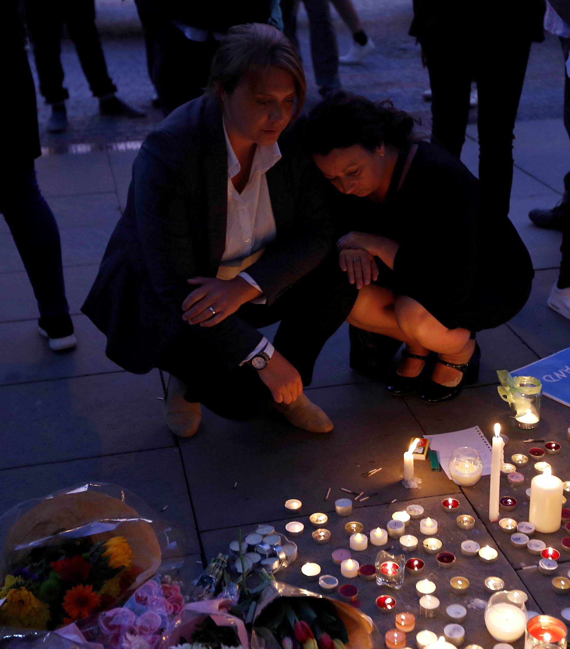 Women pay their respects to all those affected by the bomb attack, following a vigil in central Manchester