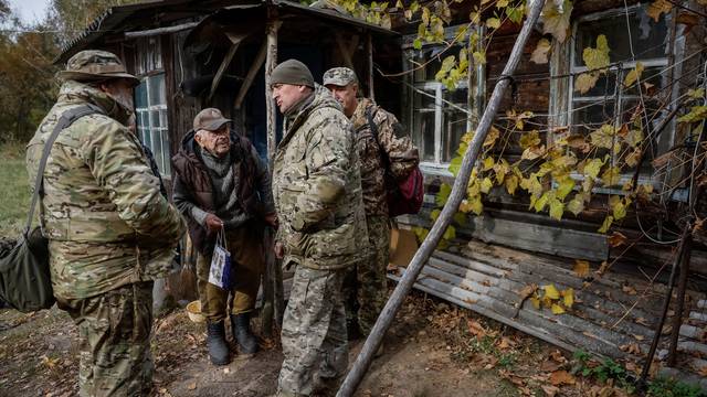 Ivan Troyanok speaks with servicemen near his house in a Chornobyl exclusion zone village