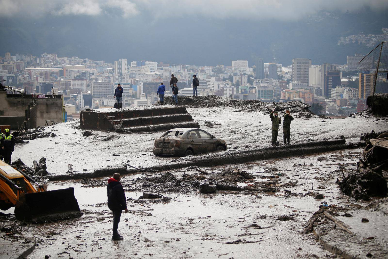 Firefighter rescue crews searching homes and streets covered by mud in Quito