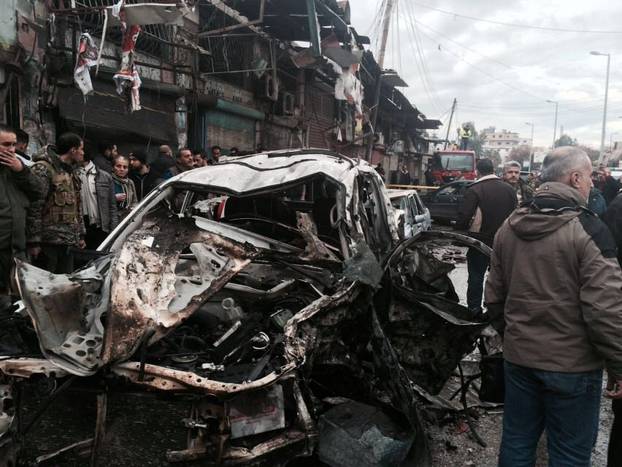 People inspect the damage at the site of a car bomb explosion, in the centre of the Syrian town of Jableh in the coastal Mediterranean province of Latakia