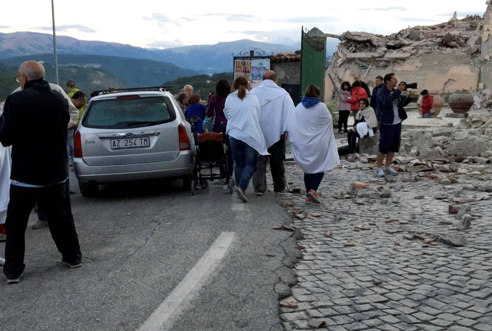 People stand along a road following a quake in Amatrice 