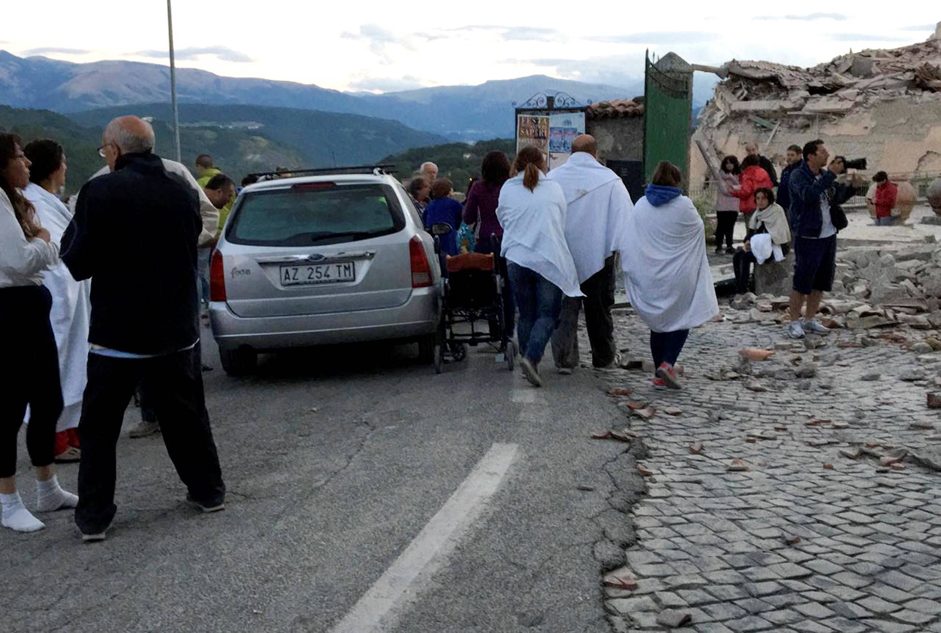 People stand along a road following a quake in Amatrice 