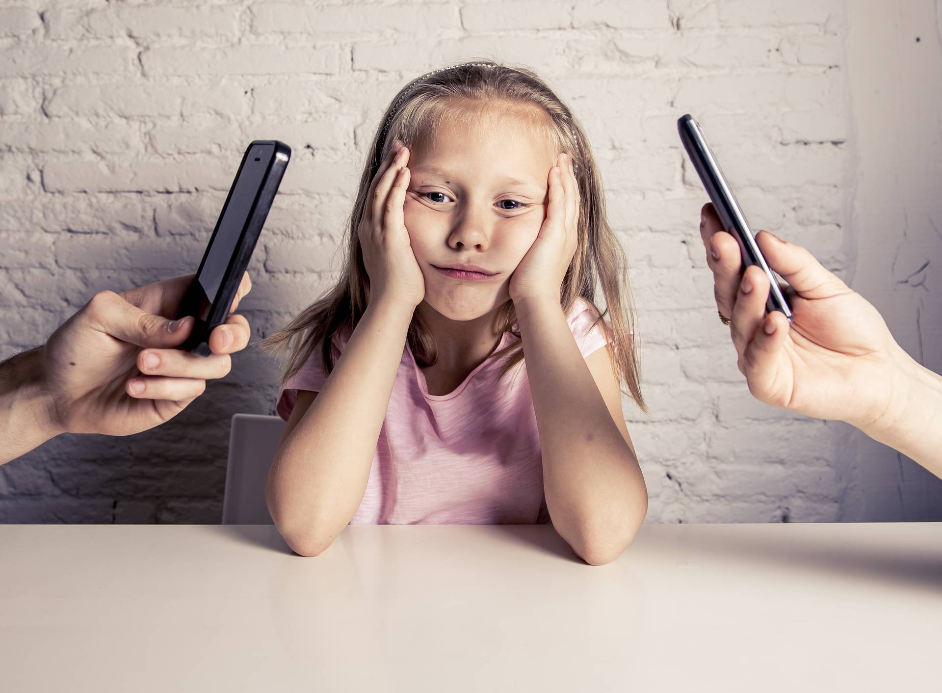 hands of network addict parents using mobile phone neglecting little sad ignored daughter bored