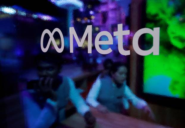 FILE PHOTO: People are seen behind a logo of Meta Platforms, during a conference in Mumbai