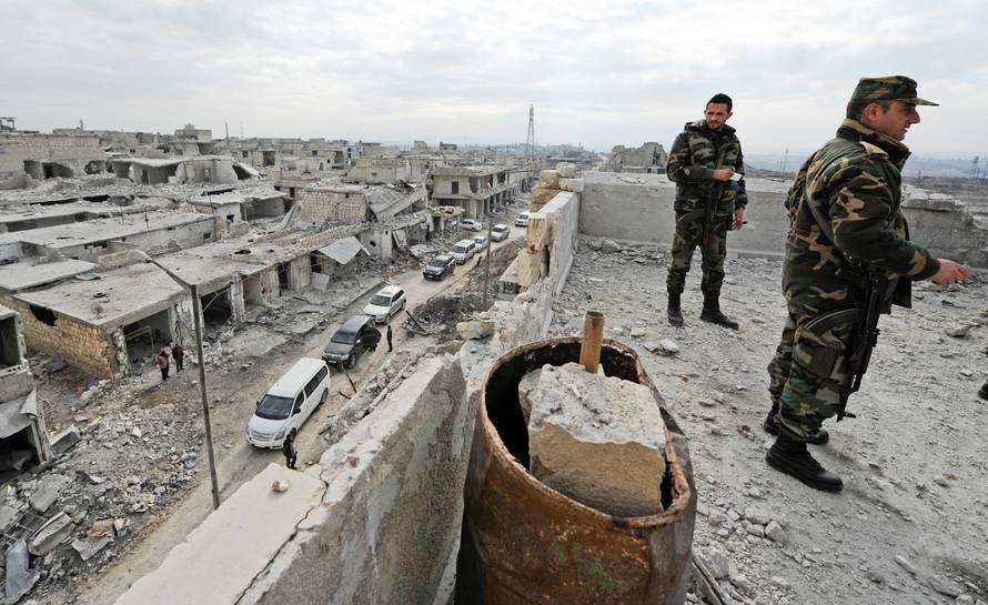 Forces loyal to Syria's President Bashar al-Assad stand atop of a building in the government held Sheikh Saeed district of Aleppo