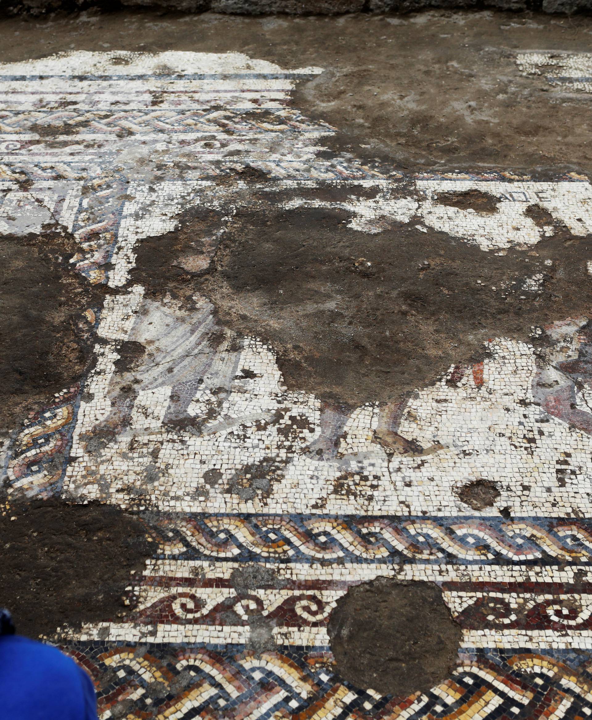 An Israel Antiquities Authority worker looks at a mosaic floor decorated with figures, which archaeologists say is 1,800 years old and was unearthed during an excavation in Caesarea