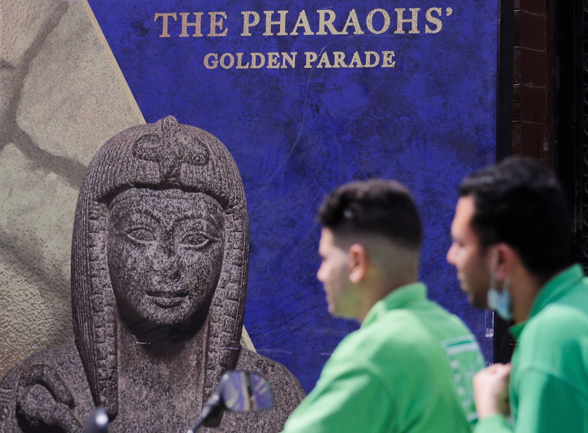 FILE PHOTO: Men pass in front of poster for pharaohs golden parade in Cairo