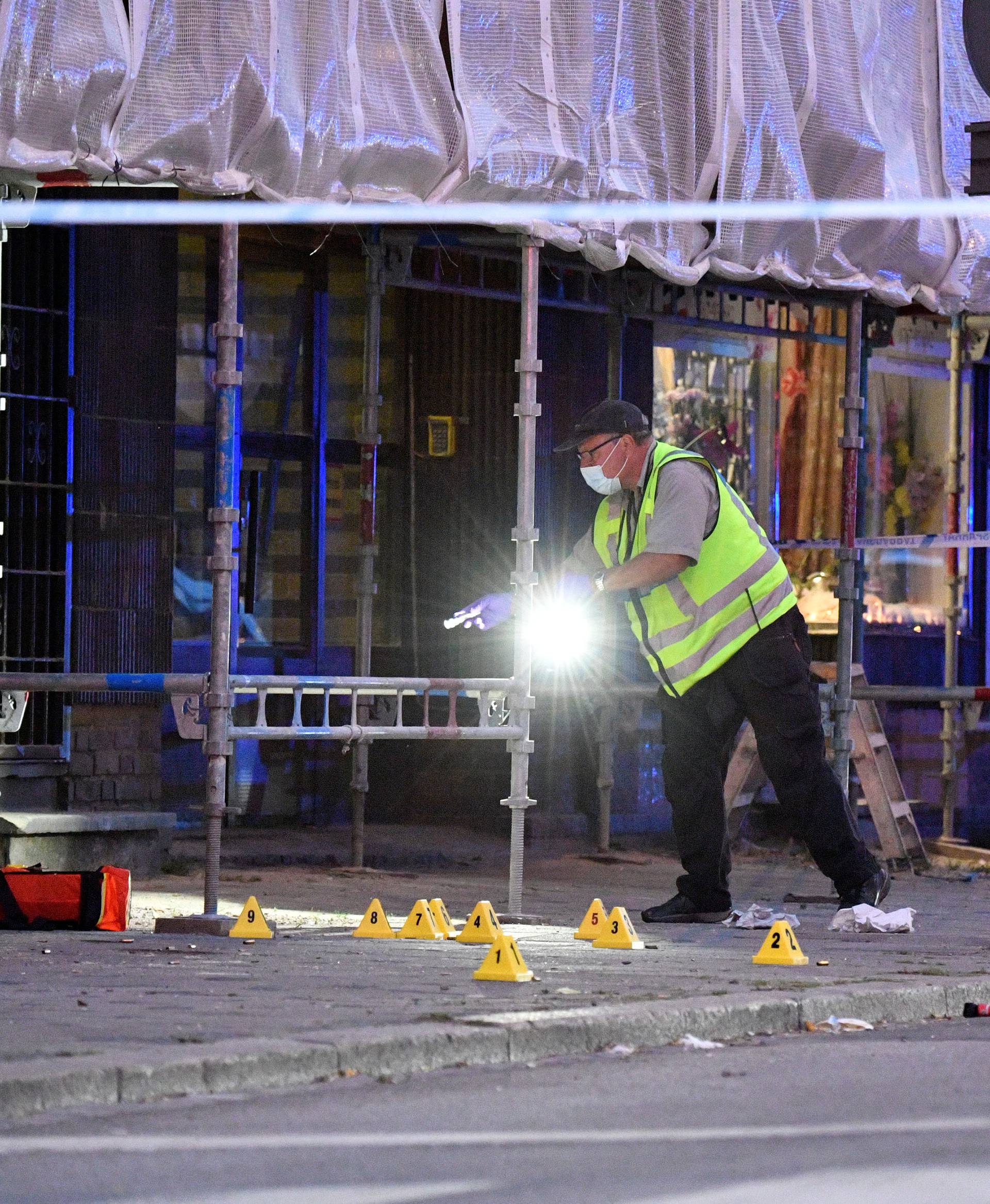 Police forensics investigate the scene after people were shot and injured outside an Internet cafe in central Malmo