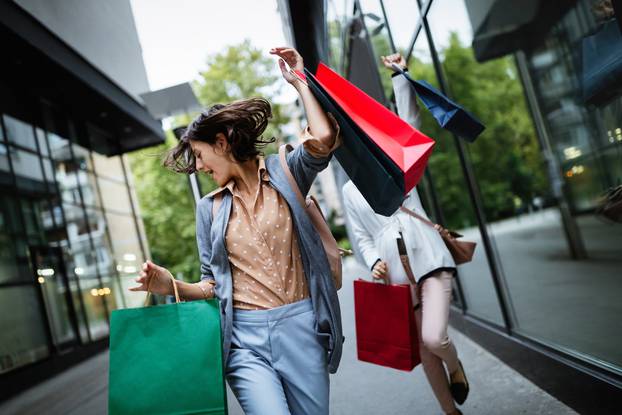 Beautiful young women with shopping bags on city street