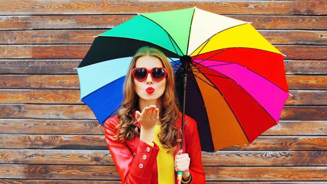 Fashion pretty woman with colorful umbrella sends air sweet kiss