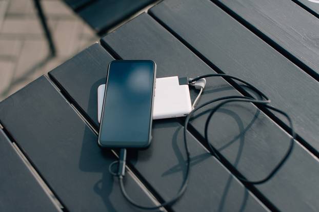 Power bank charges the smartphone on the table.