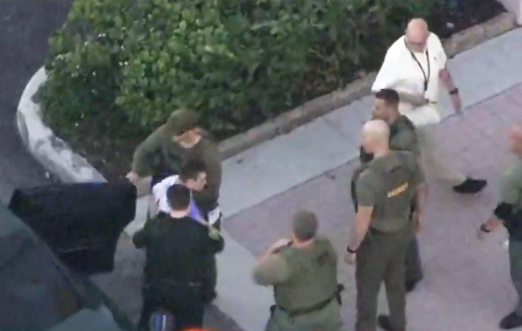 Police escort a suspect into the Broward Jail after checking him at the hospital following a shooting incident at Marjory Stoneman Douglas High School in Parkland