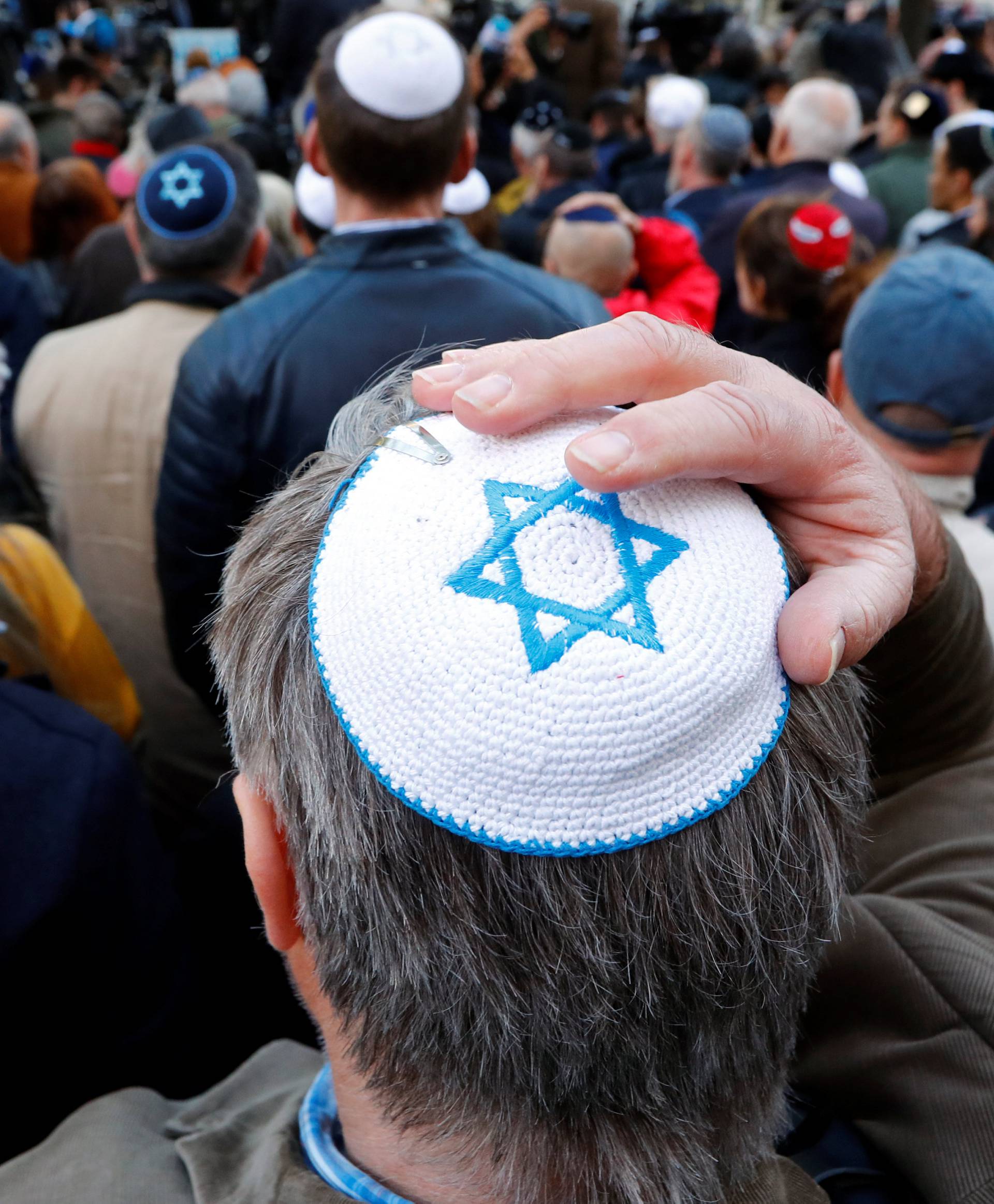 People wear kippas as they attend a demonstration in front of a Jewish synagogue in Berlin